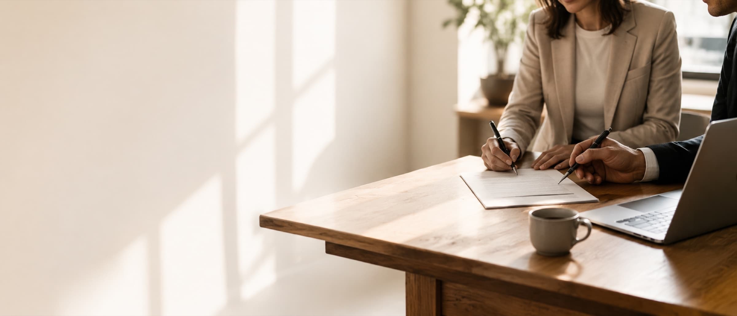 Two people signing a partnership agreement at a desk